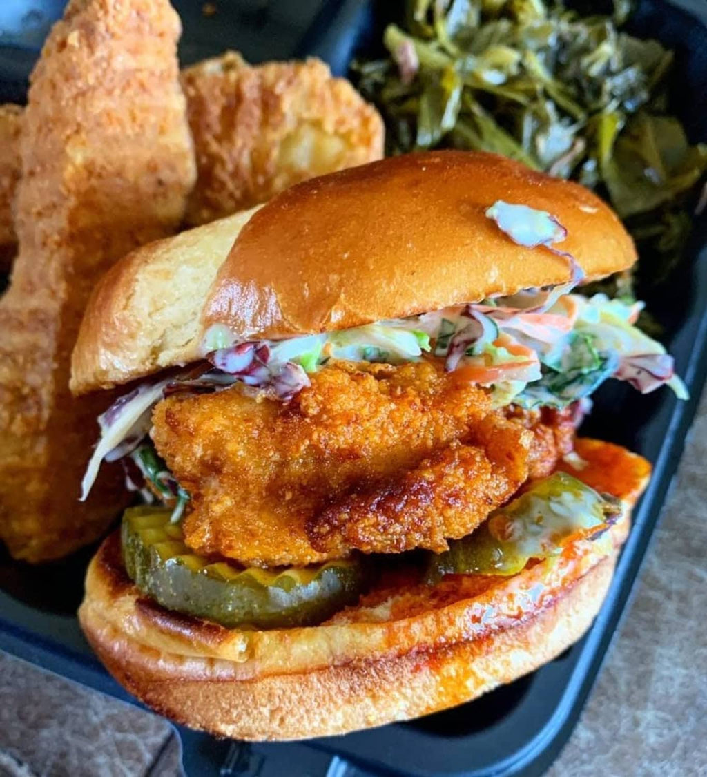 Breaded chicken sandwich on a toasted bun with lettuce and tomato in tray
