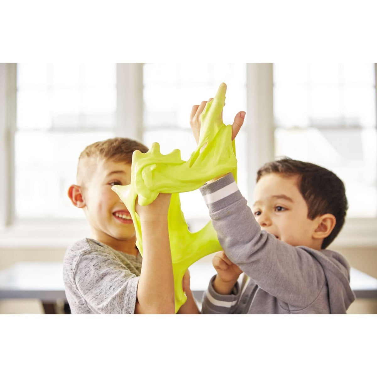 Children holding bright green slime with a school glue bottle nearby