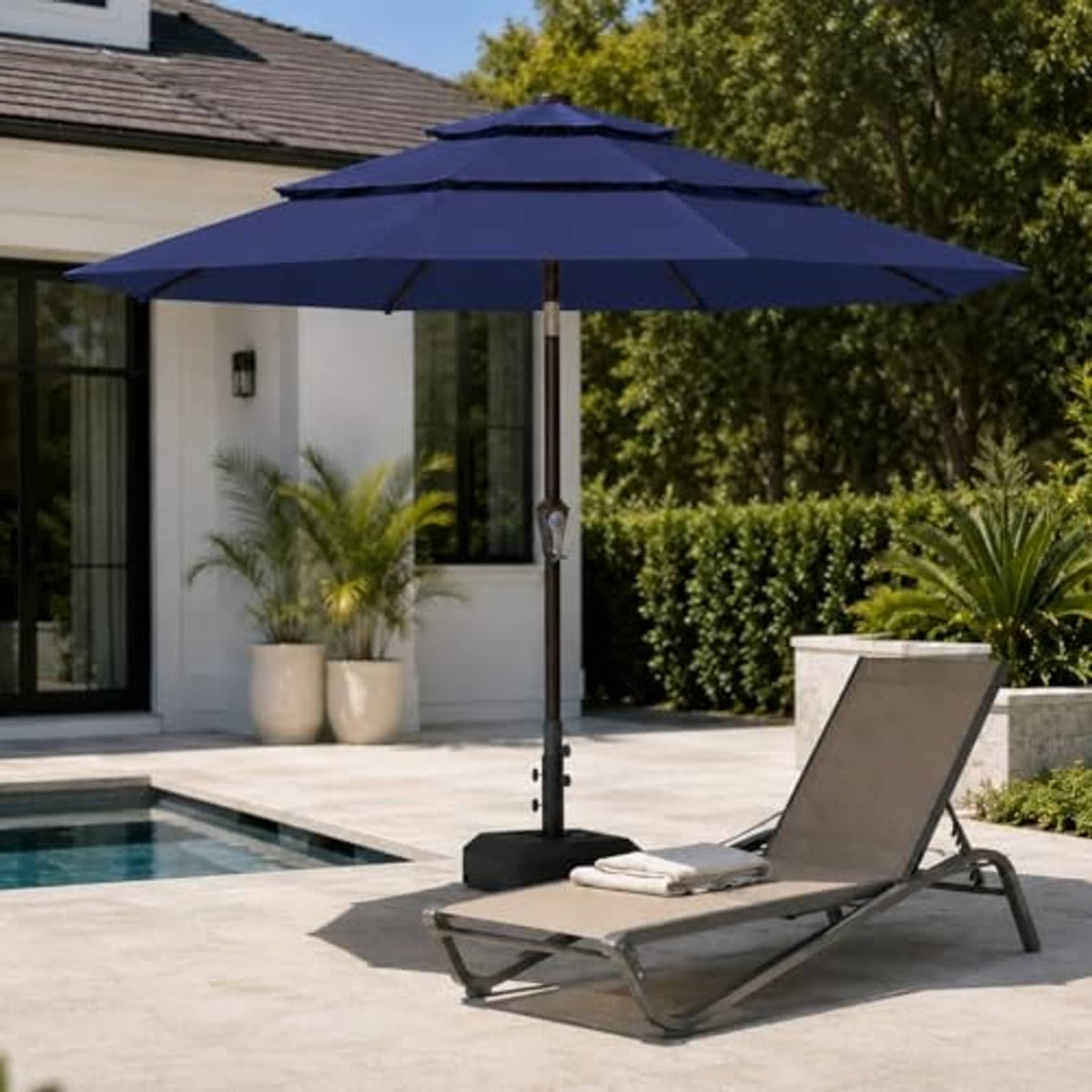 Navy 3-tier vented patio umbrella over poolside patio lounge chair and ottoman