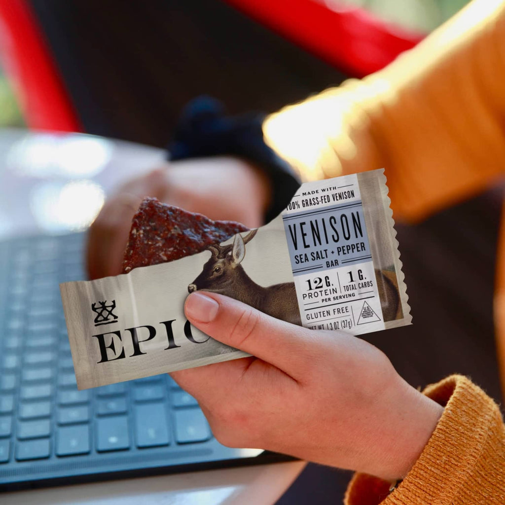Hands holding an Epic Venison Sea Salt + Pepper Bar packet with deer graphic