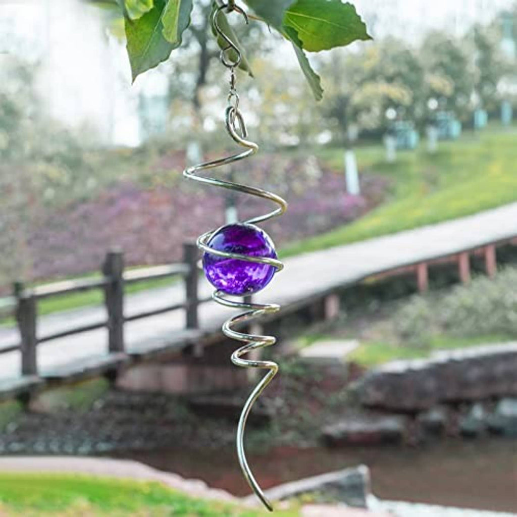 Purple gazing ball spiral wind spinner hanging on a chain over garden walkway