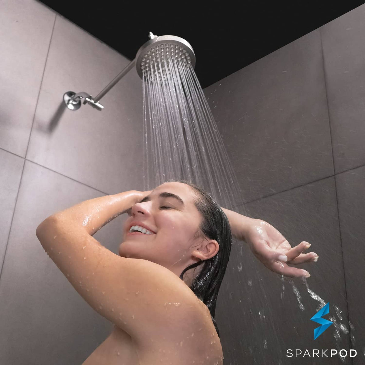 Brushed nickel rain shower head spraying water overhead onto a person