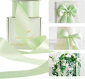 Seafoam green satin ribbon with long draped tails and a tied bow on gift boxes.