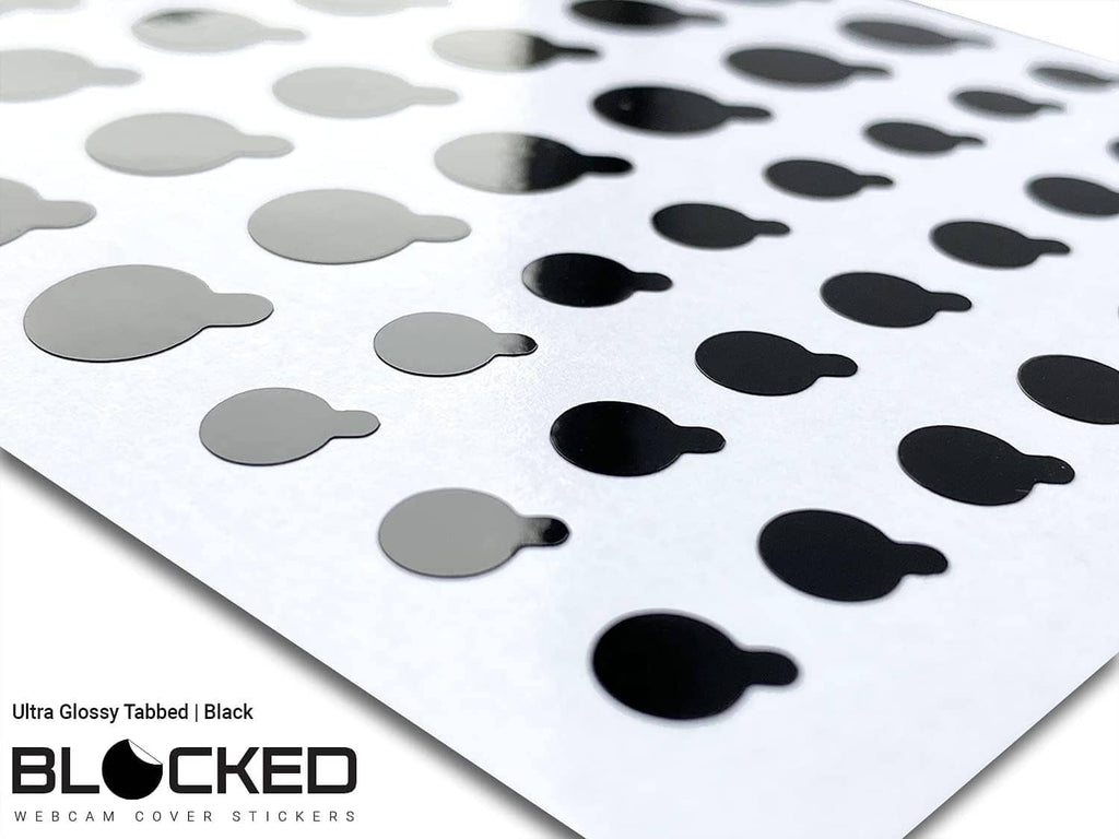 Angled close-up of black glossy tabbed privacy stickers on a white backing sheet