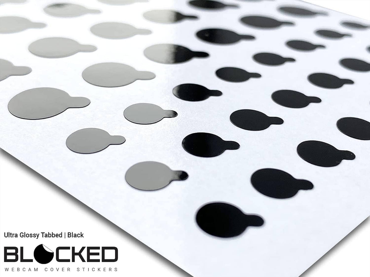 Angled close-up of black glossy tabbed privacy stickers on a white backing sheet