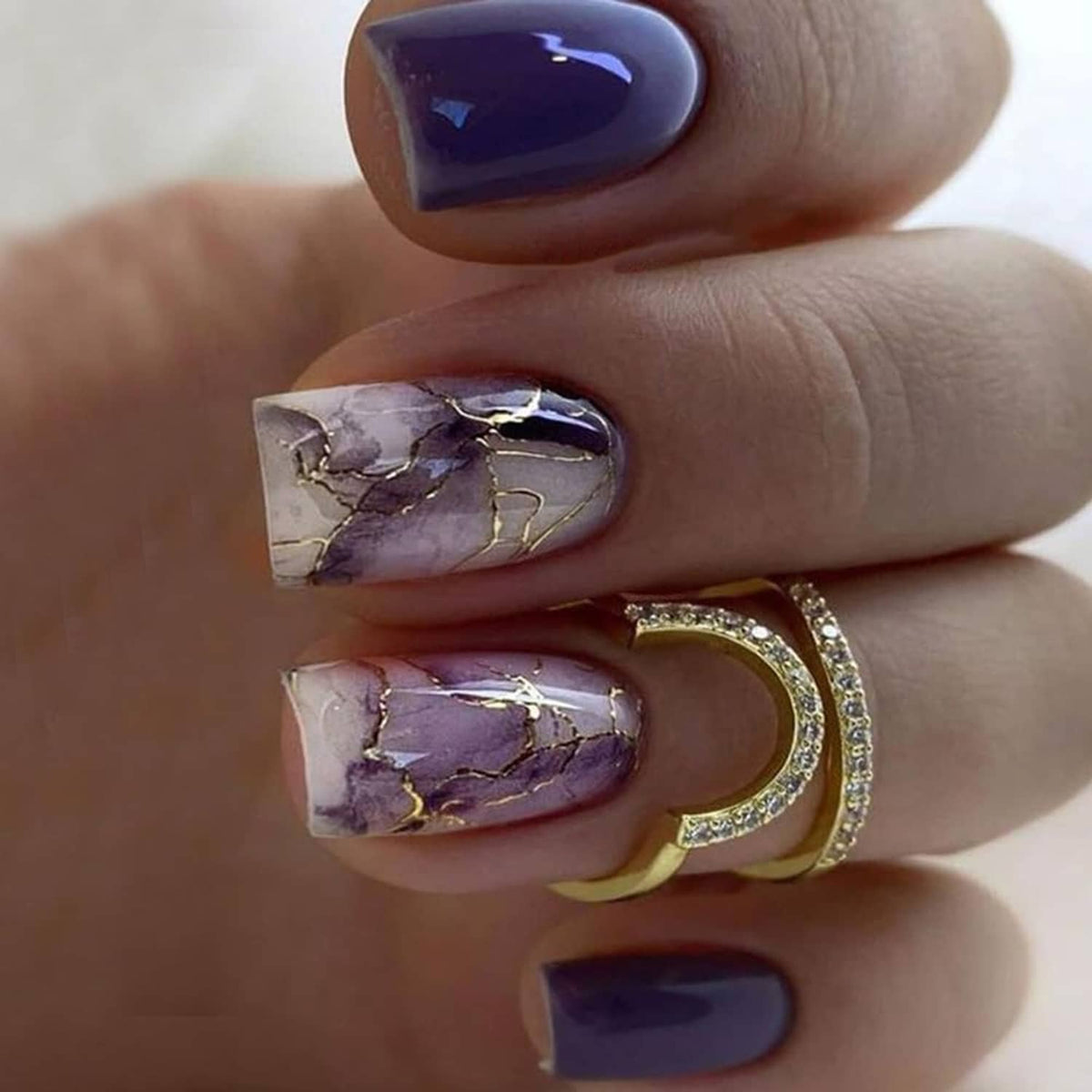 Glossy square press-on nails featuring purple marble print and gold stripe detailing