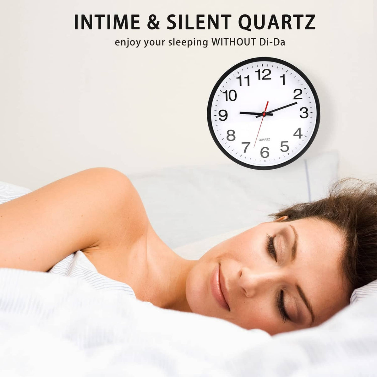 Black round wall clock with white dial and black numerals, red hands mounted above bedding.