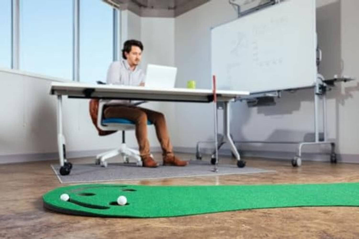 Dark green golf putting green mat with several balls and cup holes on the floor