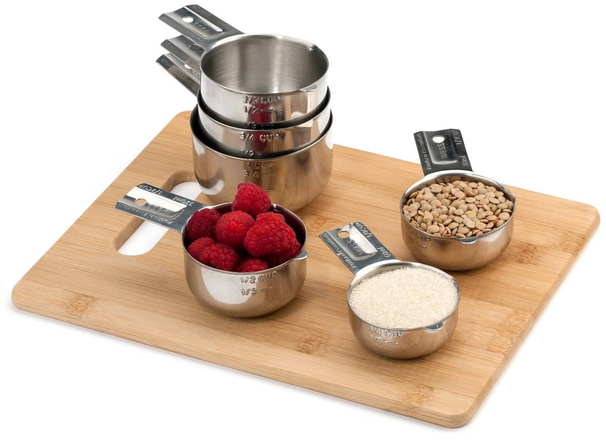 6 stainless steel measuring cups on a wooden board with ingredients inside