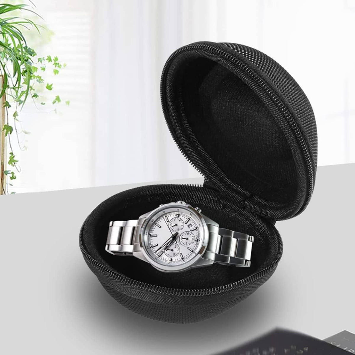 Open black watch case holding a silver metal wristwatch on molded insert