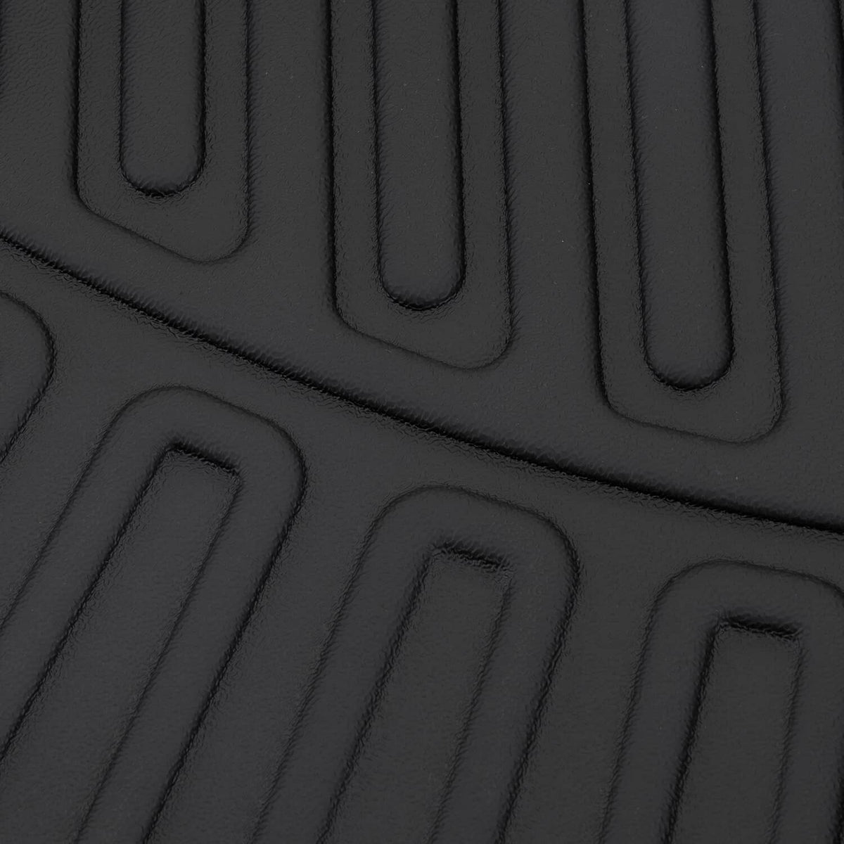Black floor mat surface with raised channels and ridged texture