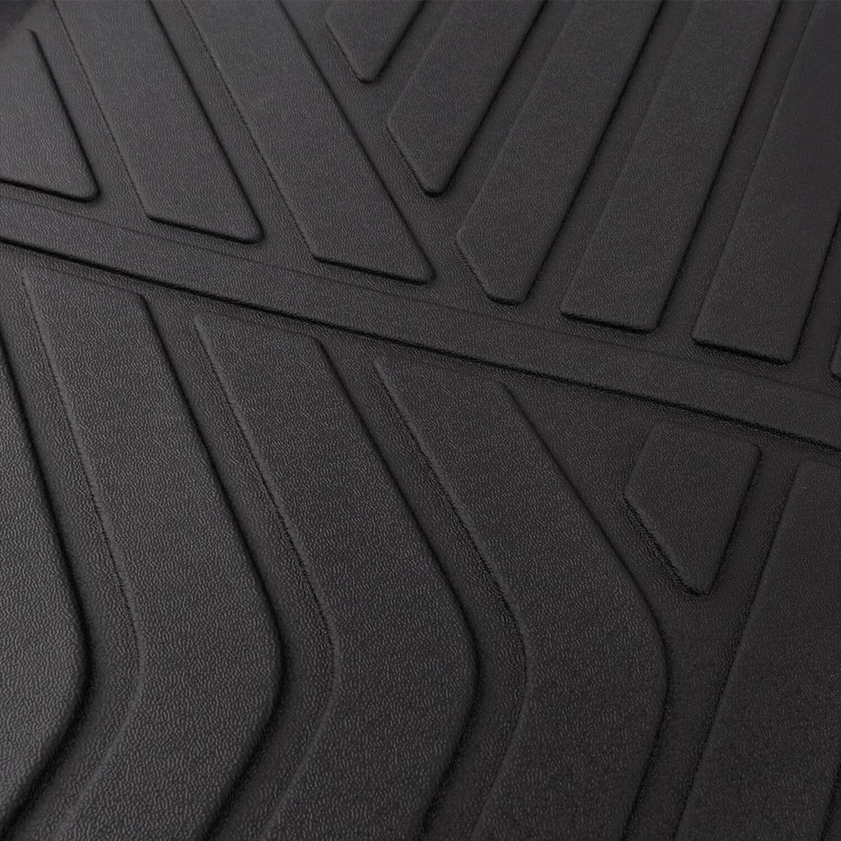 Close-up of black floor mat tread texture with deep curved grooves for grip