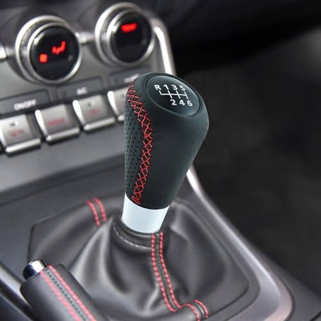 Manual shifter knob installed in car interior, black leather with red stitched grille and shift numbers