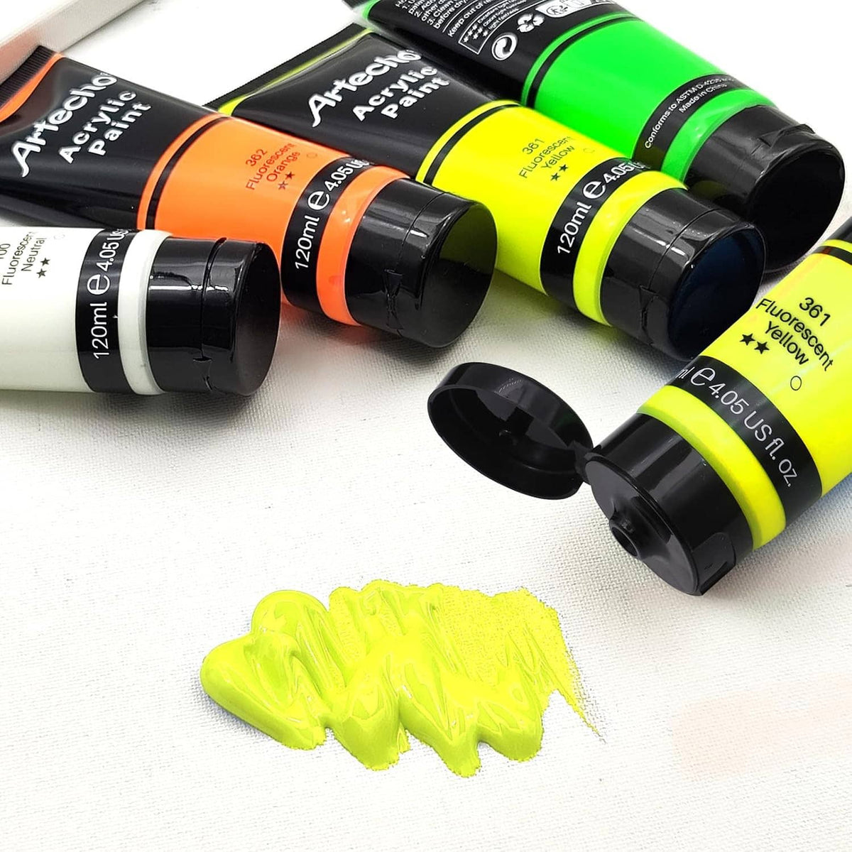 Assorted acrylic paint bottles with a dollop of fluorescent yellow paint