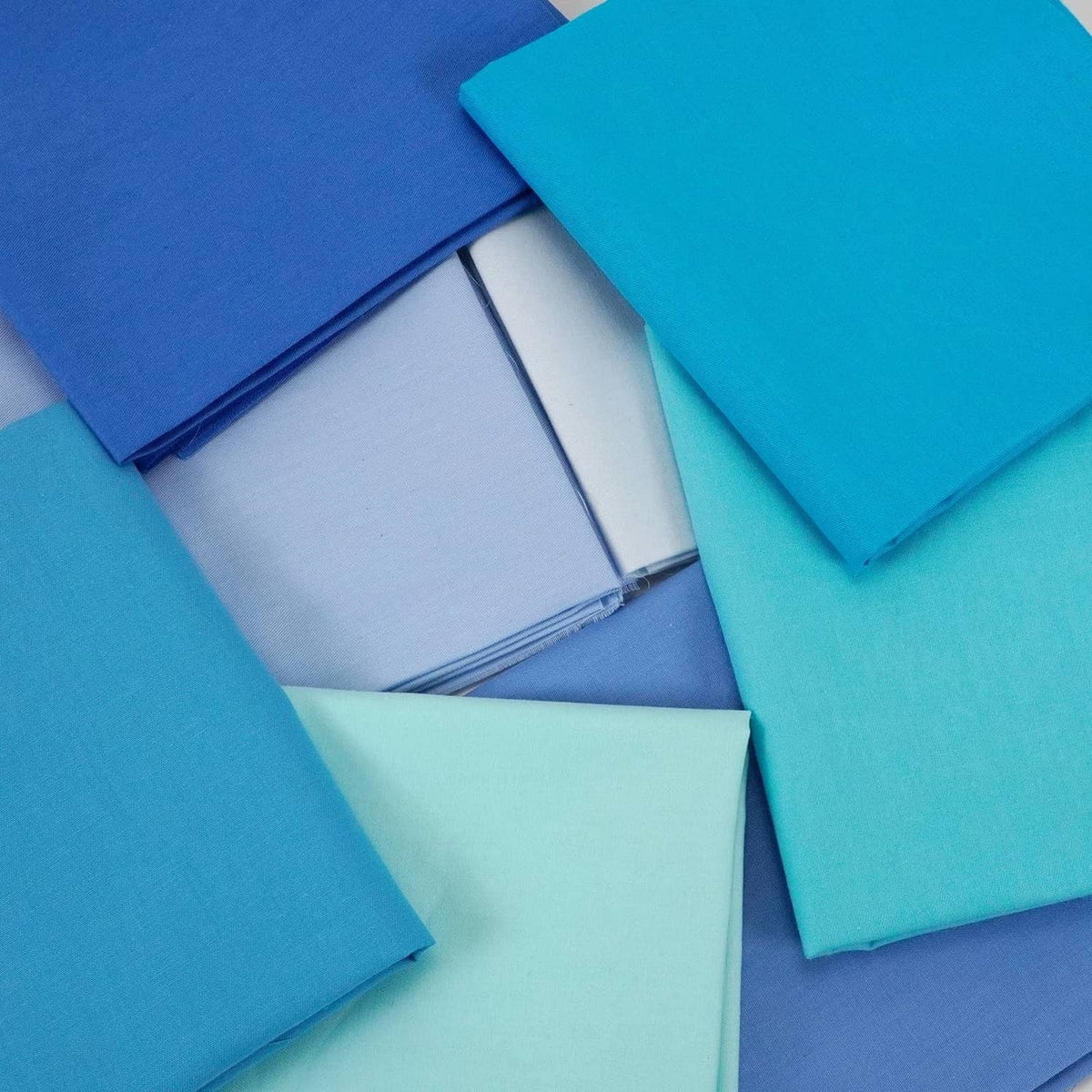 Assorted solid cotton fabric pieces in blue and aqua, neatly folded