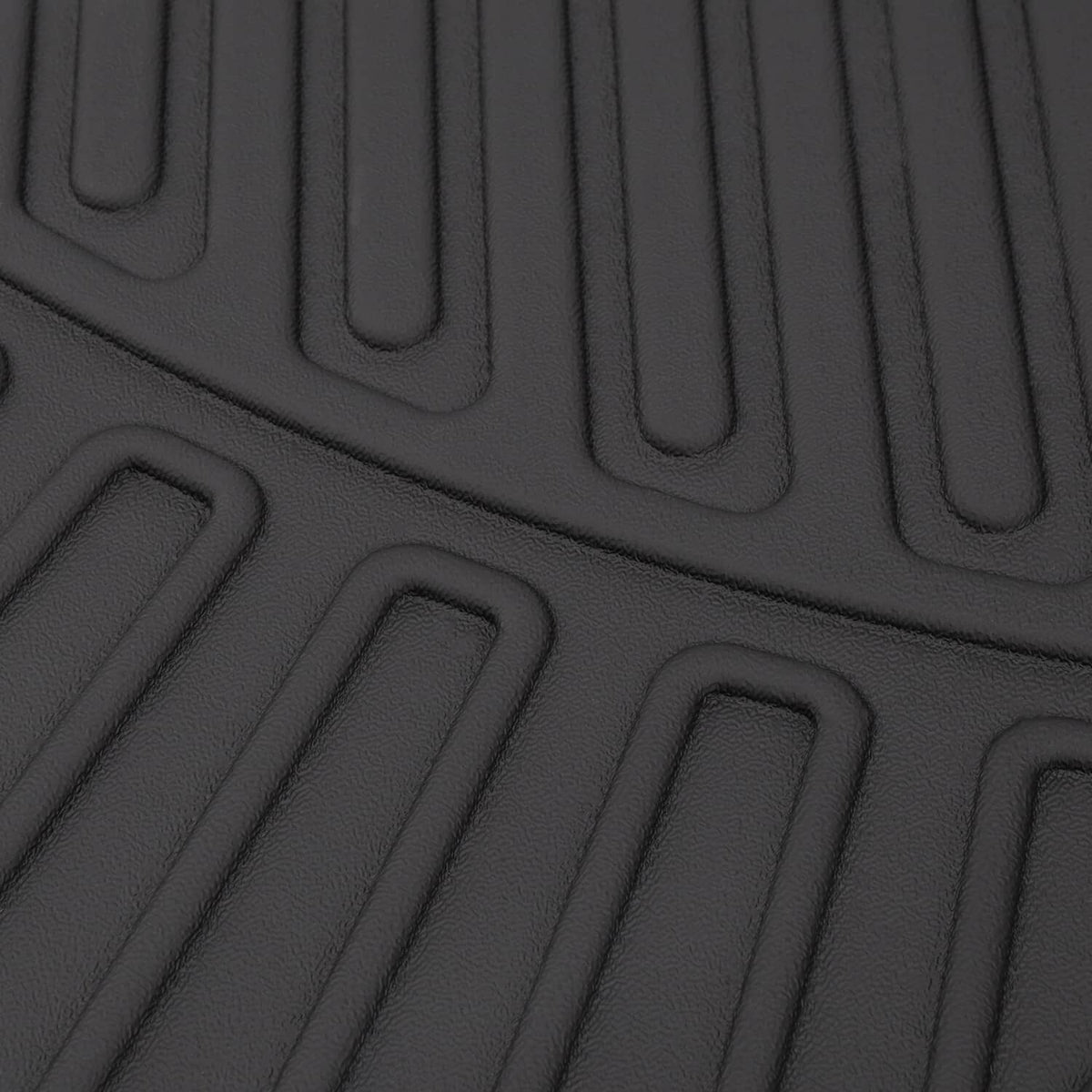 Close-up of black rubber floor mat texture with raised channels and grip grooves