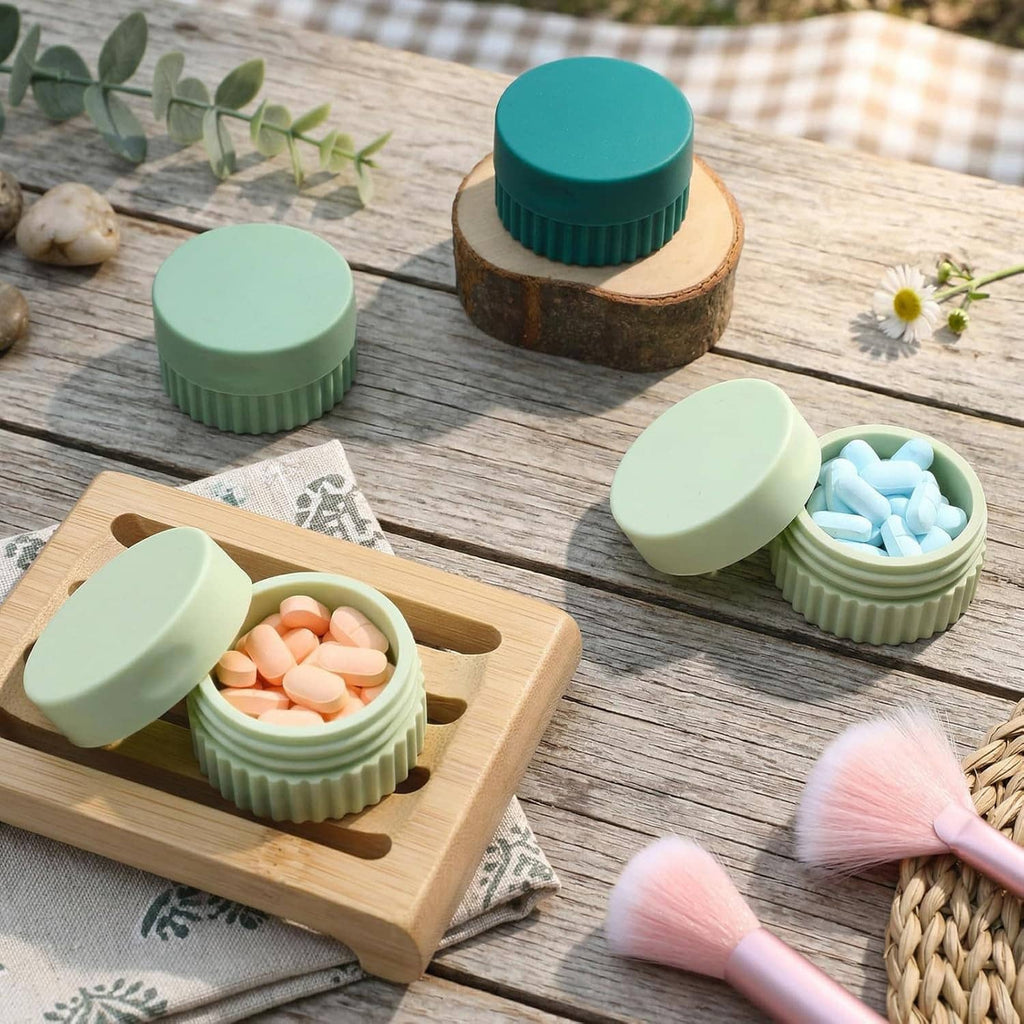 Small silicone travel jars on a wooden board, lids open with colored contents inside