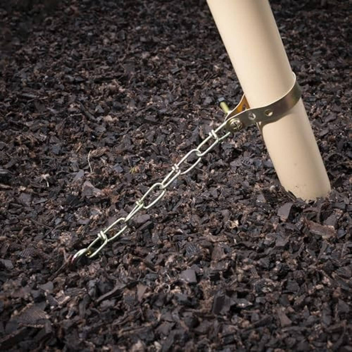 Corkscrew ground anchor with chain attached to pole in dark mulch