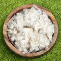 Kapok fiber fill, loose white fluff in round wooden bowl.