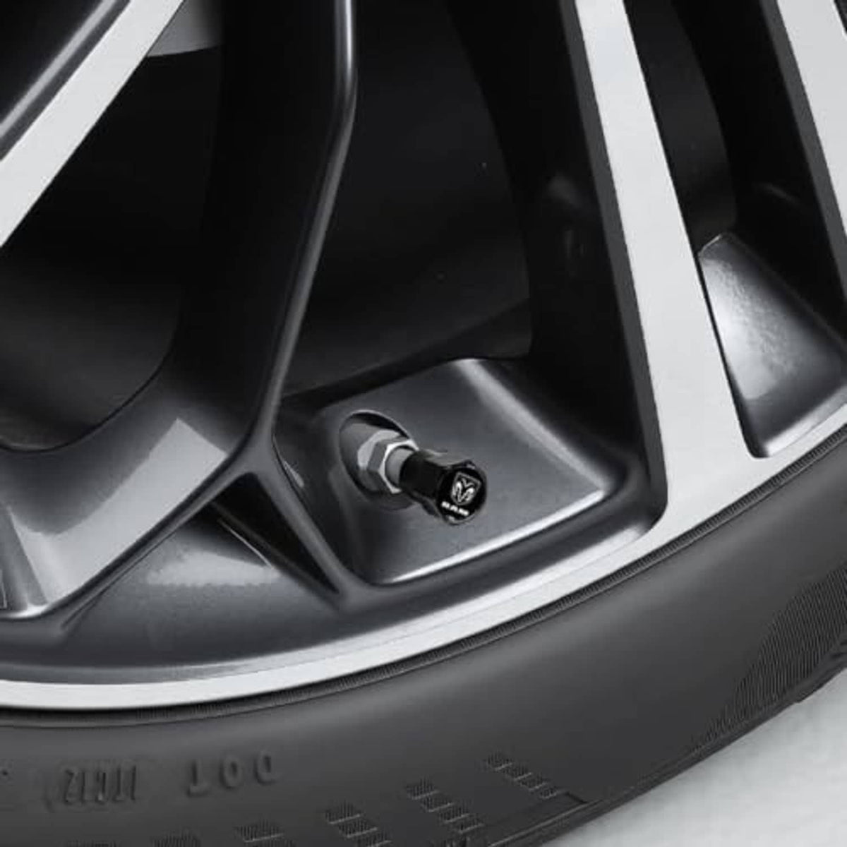 Black octagonal valve stem cap with RAM logo installed on wheel rim