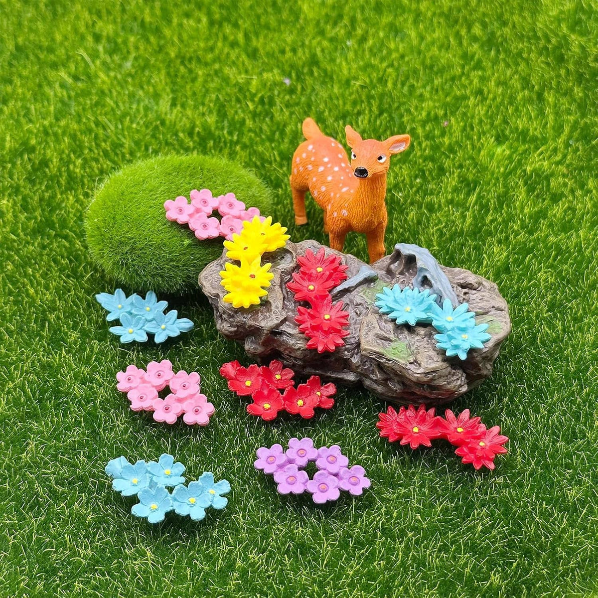 Mini resin flowers around a small fox figurine on green grass