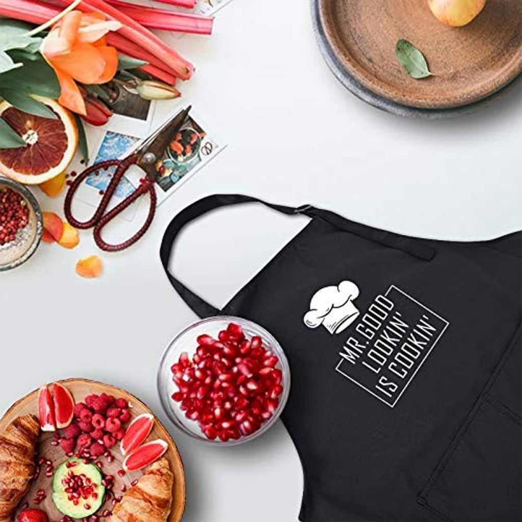 Black chef apron laid flat with "Mr. Good Lookin' is Cookin" logo and neck strap