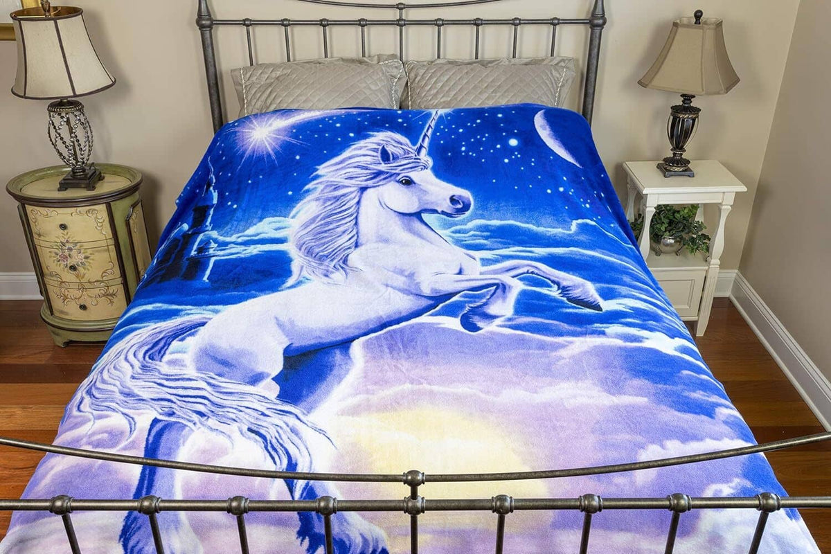 Unicorn plush throw blanket on bed, blue starry sky with white unicorn graphic