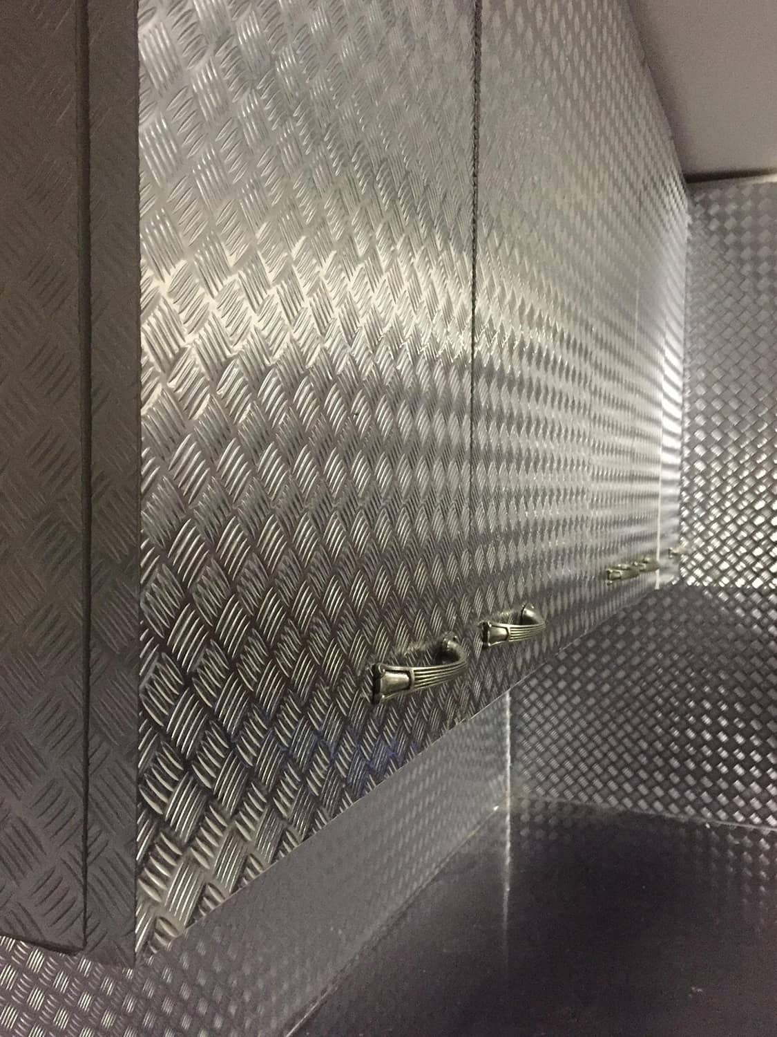 Diamond-plate metallic chrome vinyl wrap corner panel with reflective texture