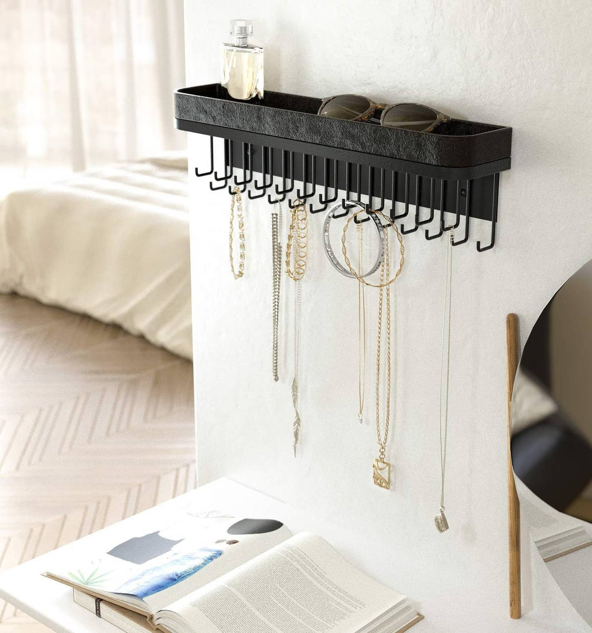 Black wall jewelry organizer with front necklace hooks and recessed top tray