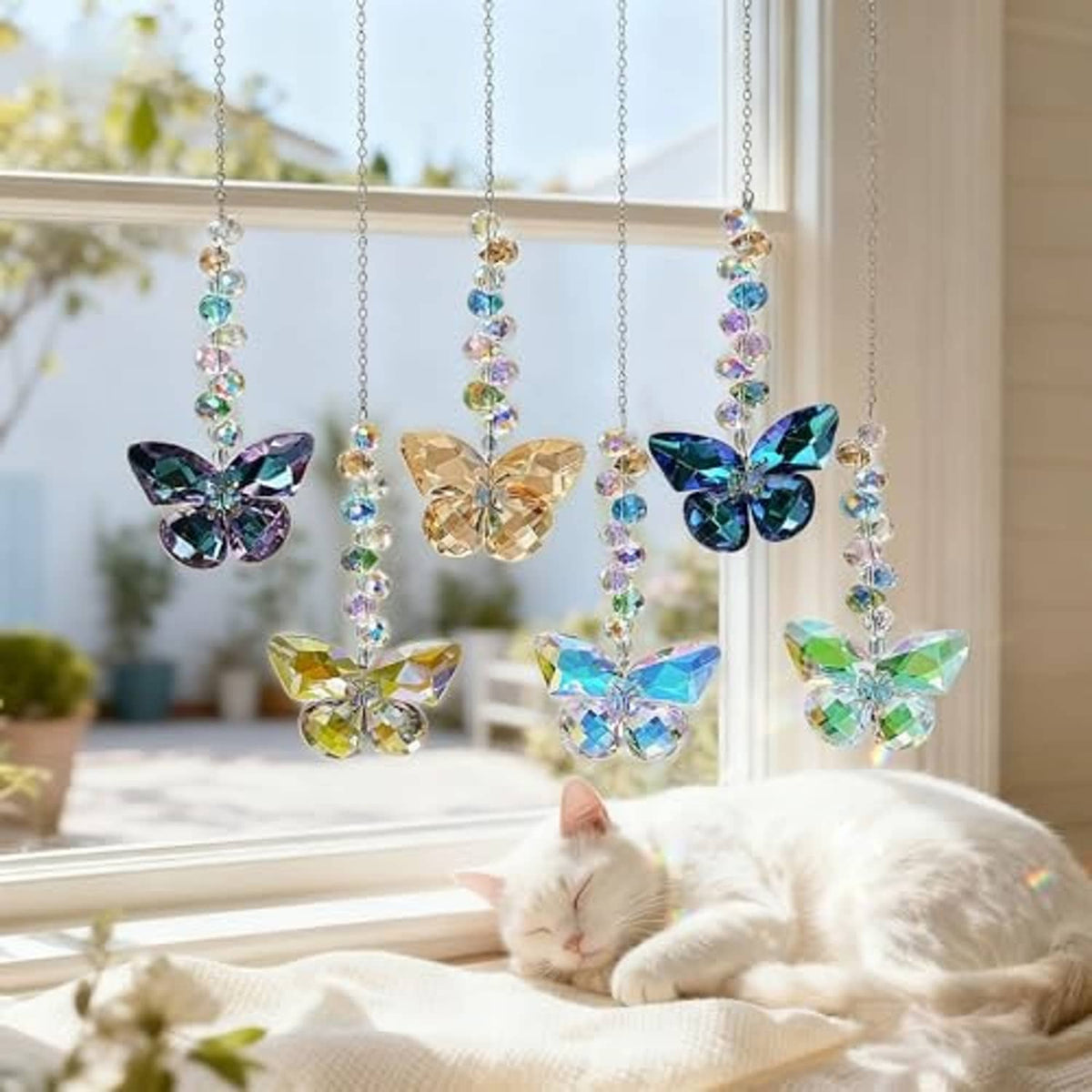 Hanging crystal butterfly suncatchers by a window with cat resting nearby