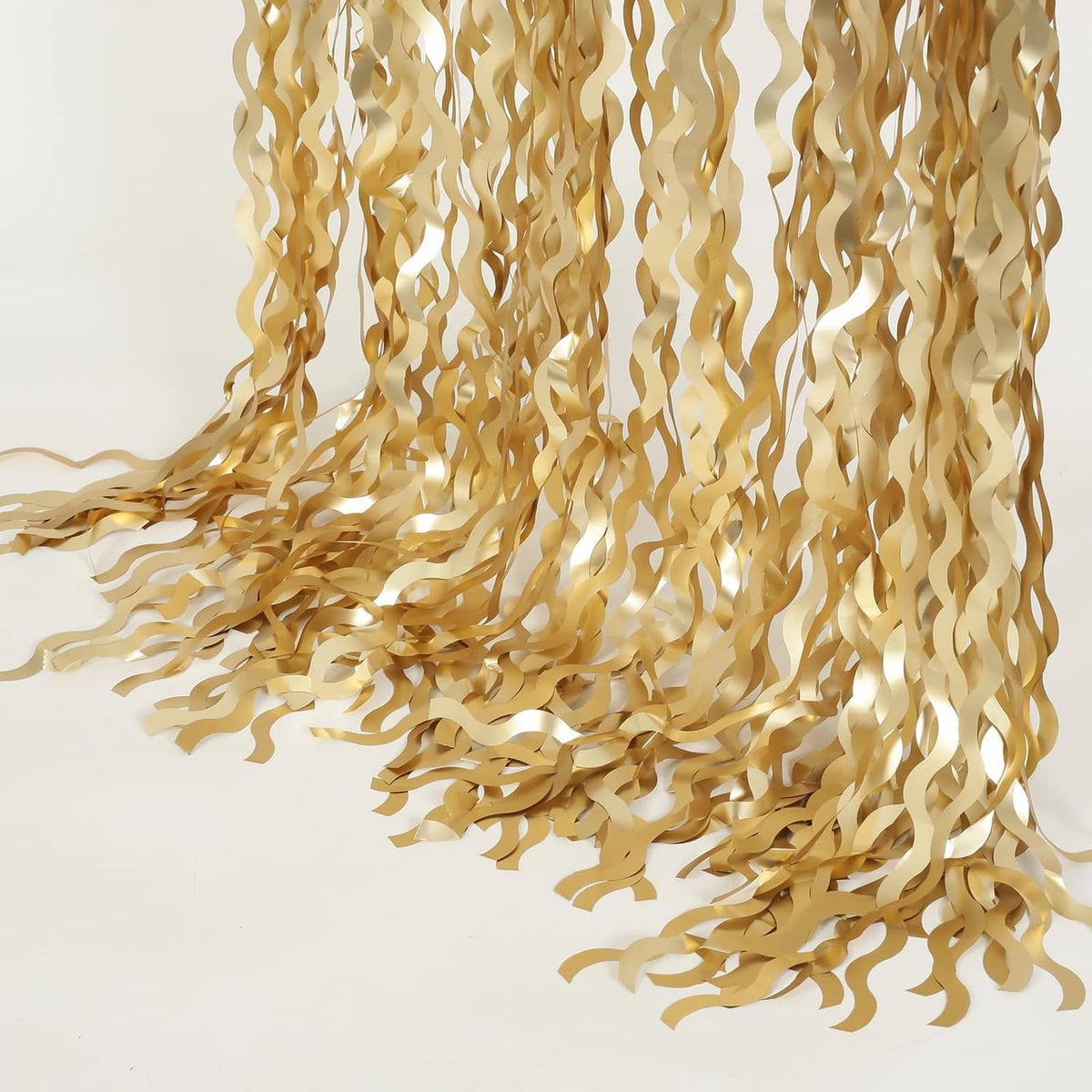 Champagne gold metallic tinsel foil curtain with cascading wavy strands, corner view