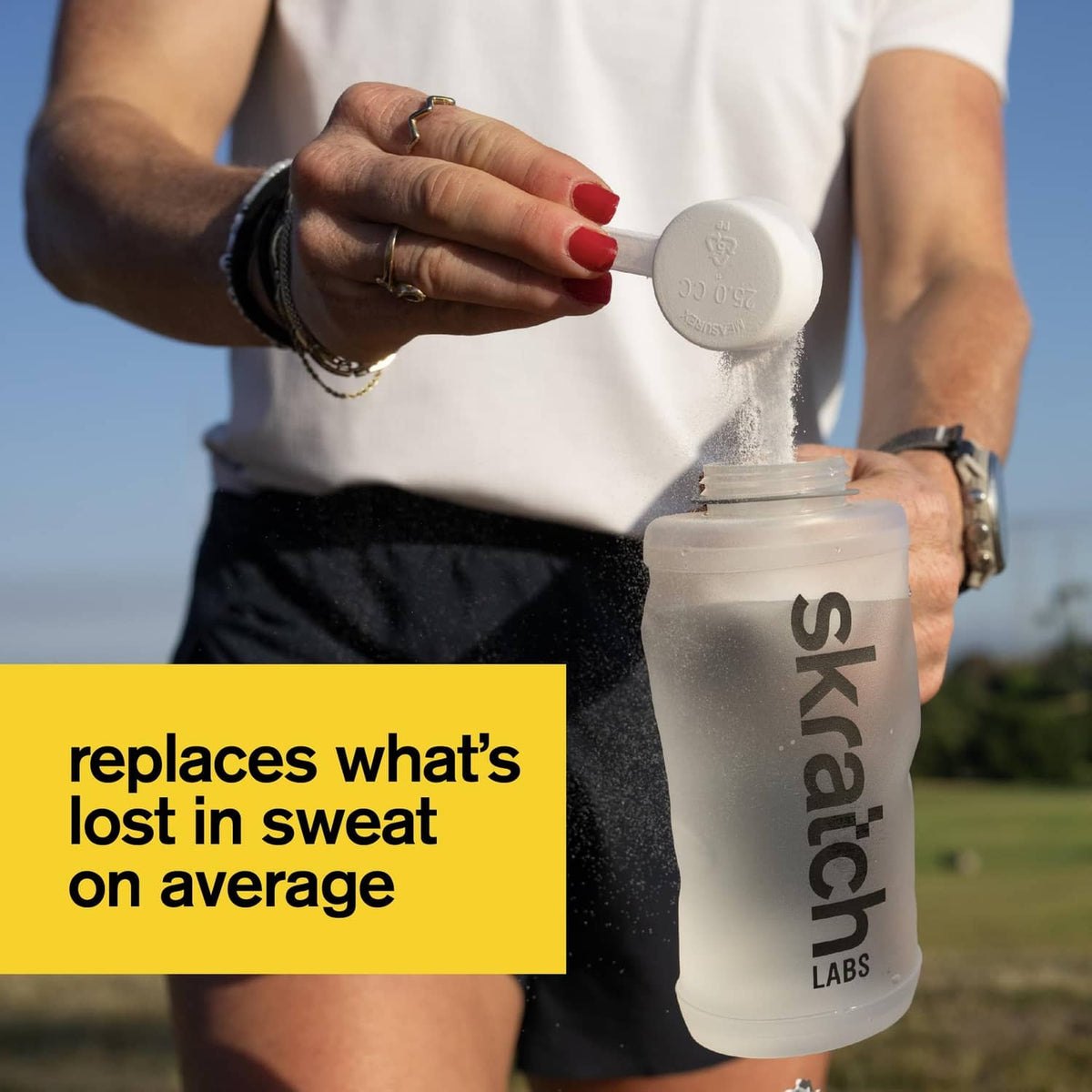 Sports drink mix shaker bottle with powder pouring into a bottle by a person