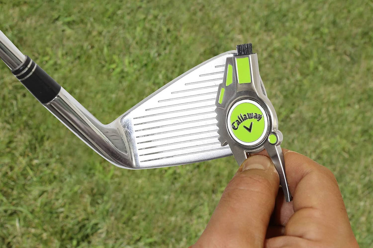 Hand using 4-in-1 golf divot repair tool on a golf club, lime details