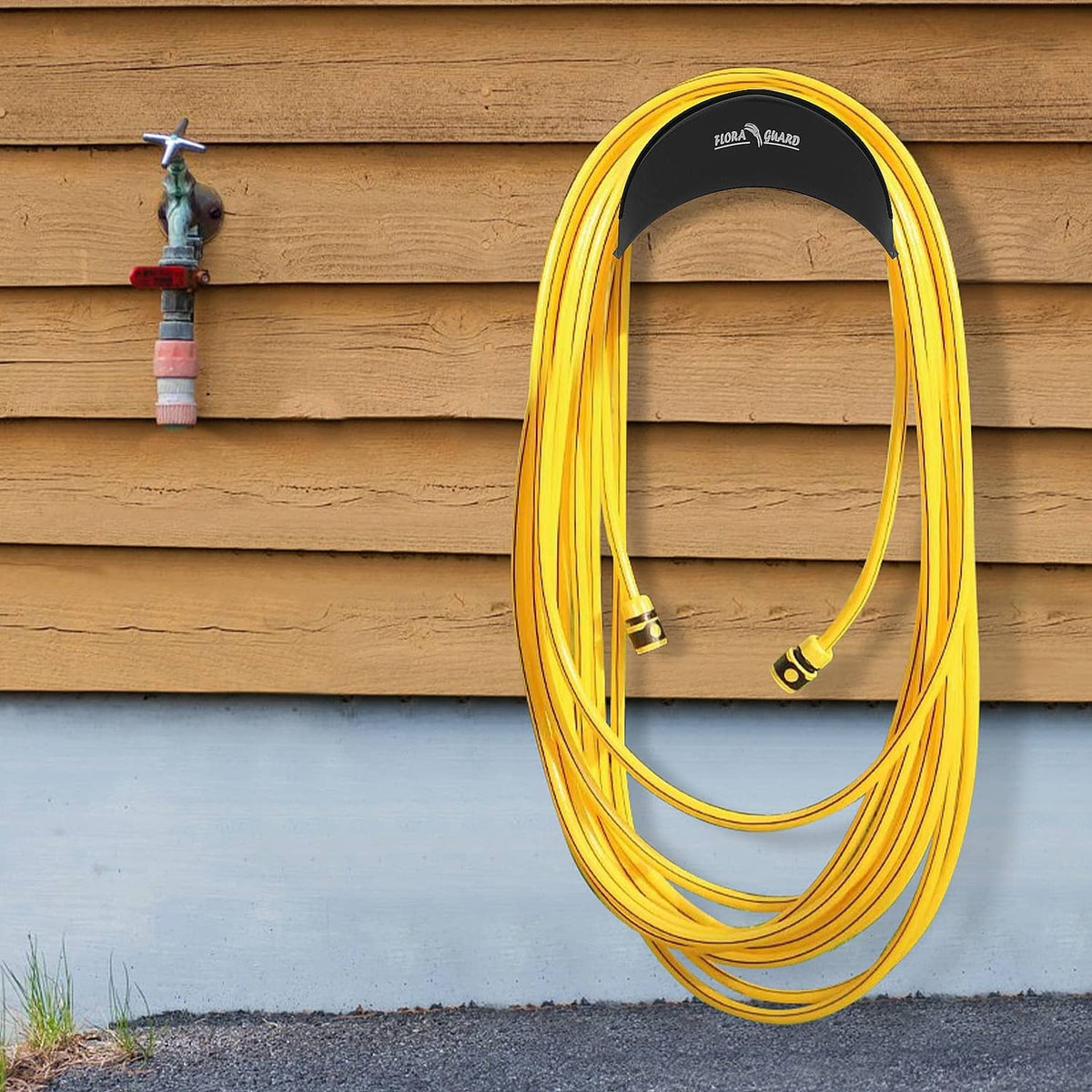 Black hose hanger holding a coiled yellow garden hose against a wooden wall