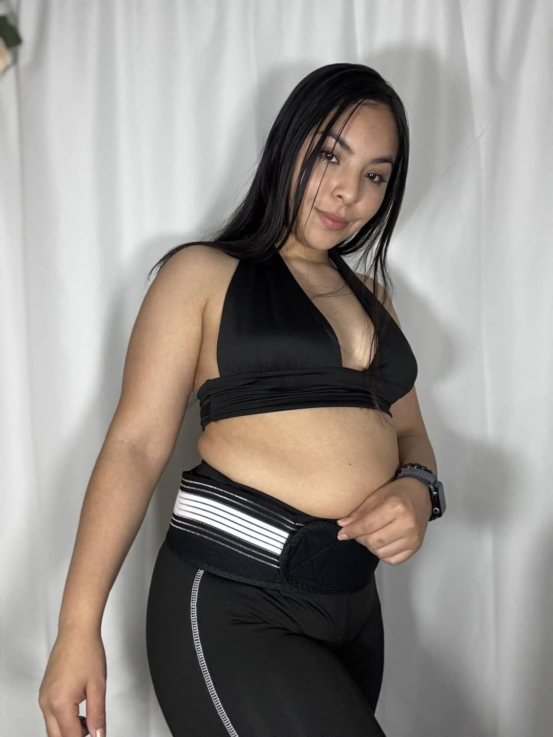 Black compression belt with white stripe detail worn around hips on a seated model