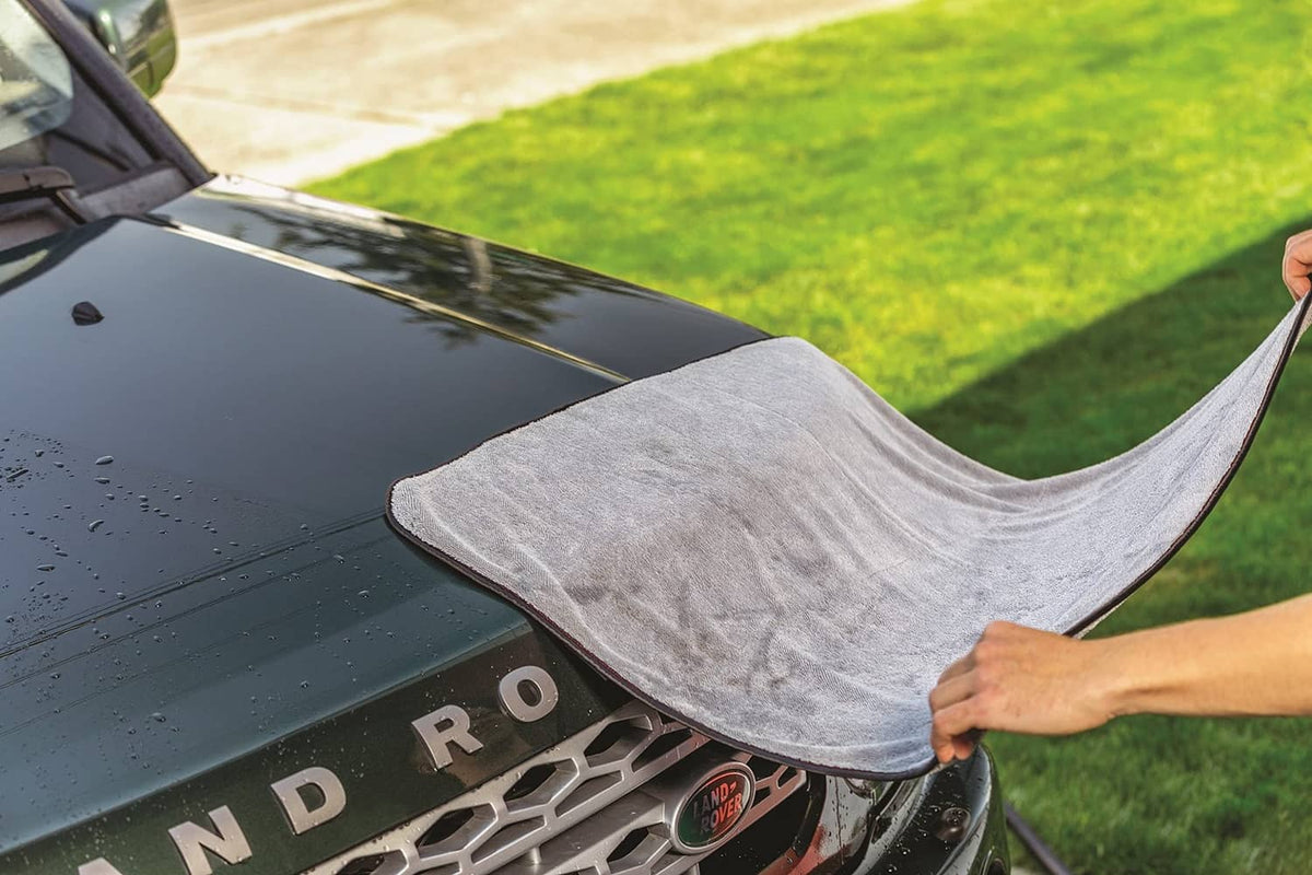 Car hood being waxed with a gray microfiber cloth