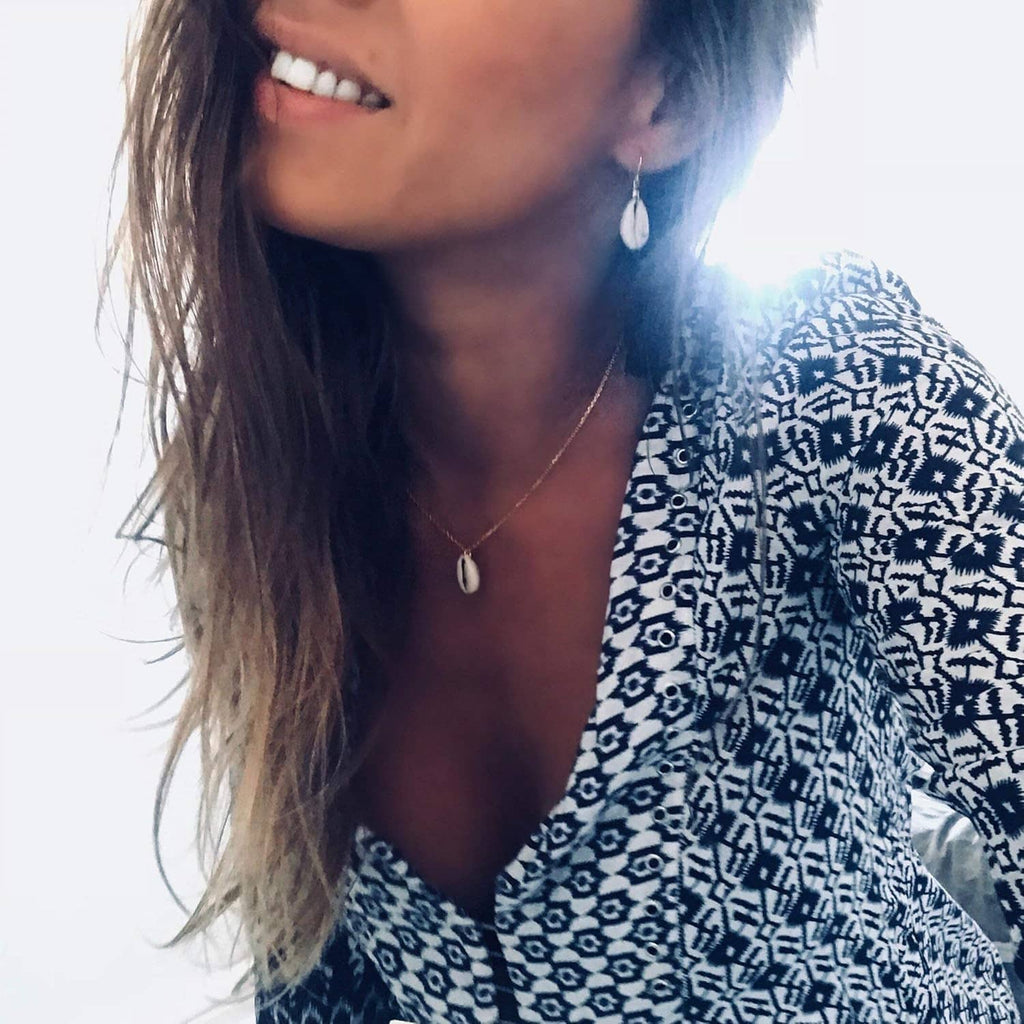 Gold-tone necklace with small shell pendant resting at the collarbone