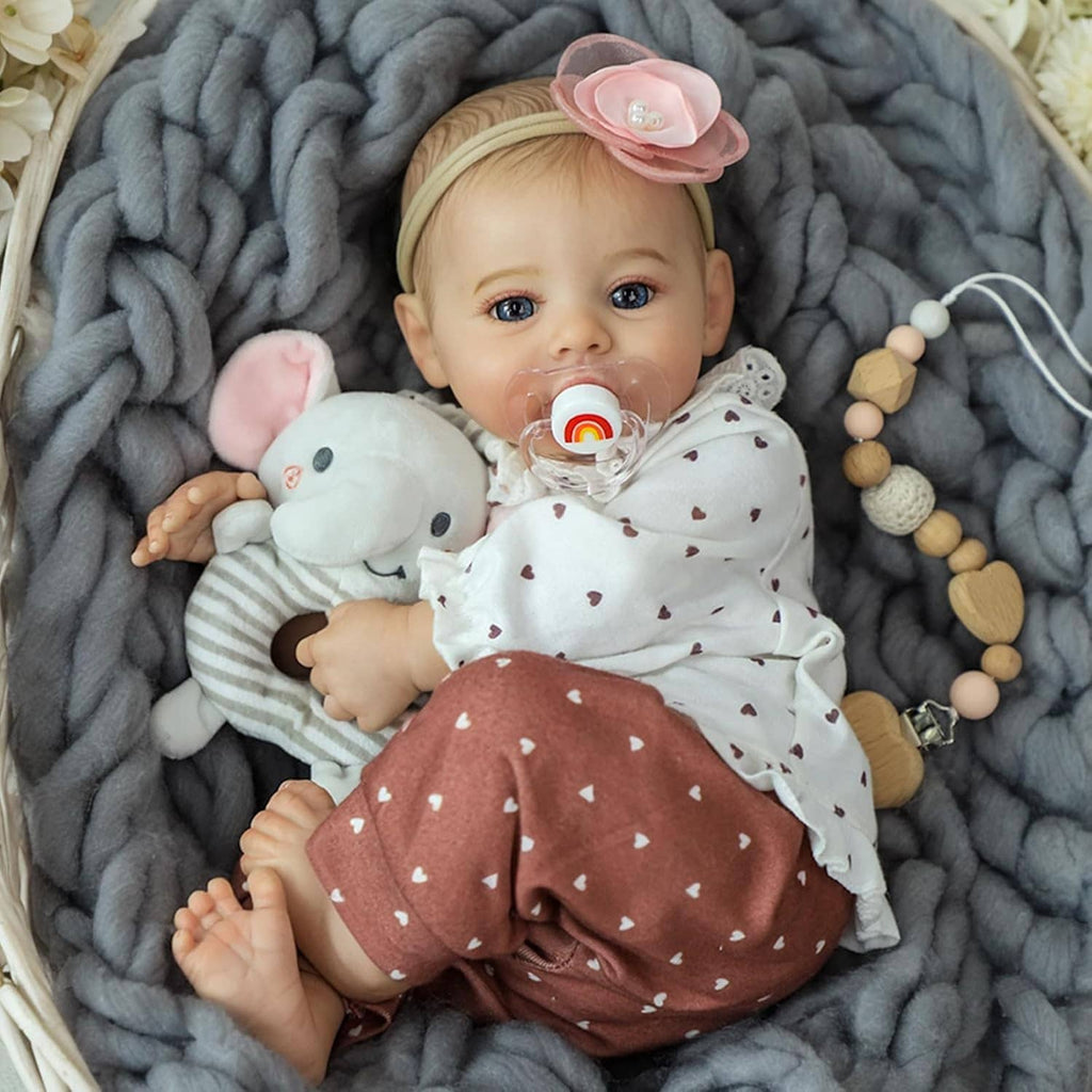 Realistic 18-inch reborn baby girl doll lying down with plush mouse toy and pacifier.