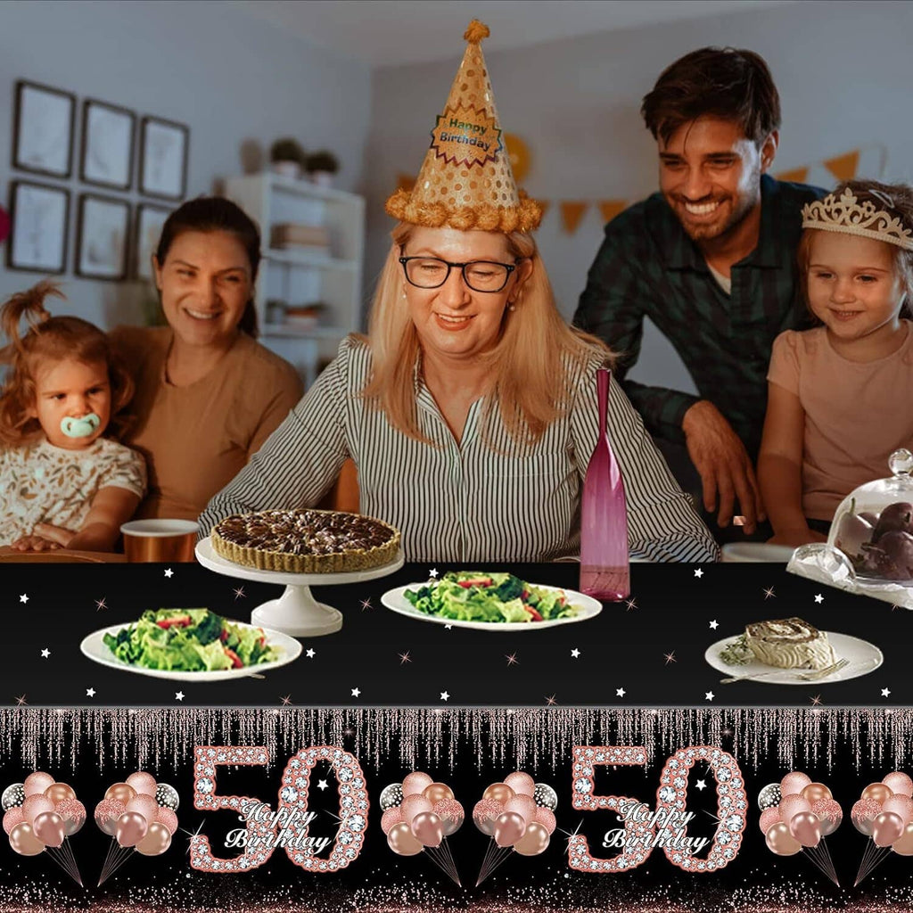Black birthday tablecloth with large “50” numbers, star accents, and rose-gold balloon decoration