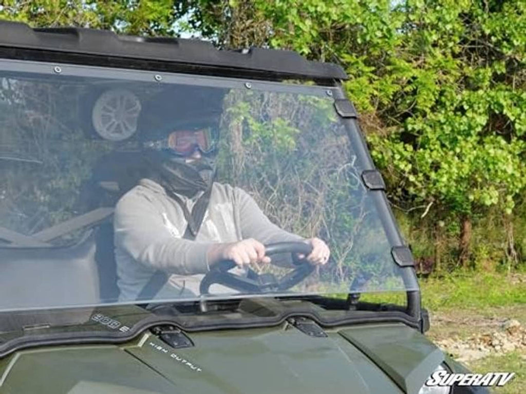 Close-up of clear windshield panel and black mounting frame on green UTV