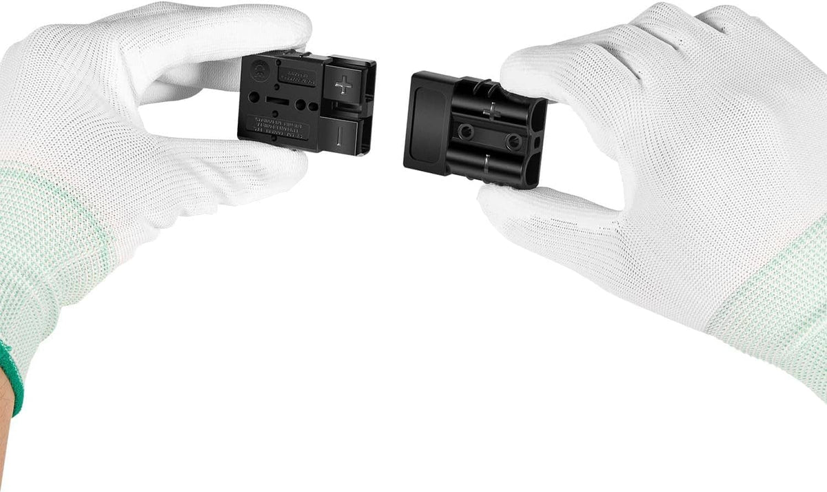 Hands holding black quick connect plug connectors with red wire leads