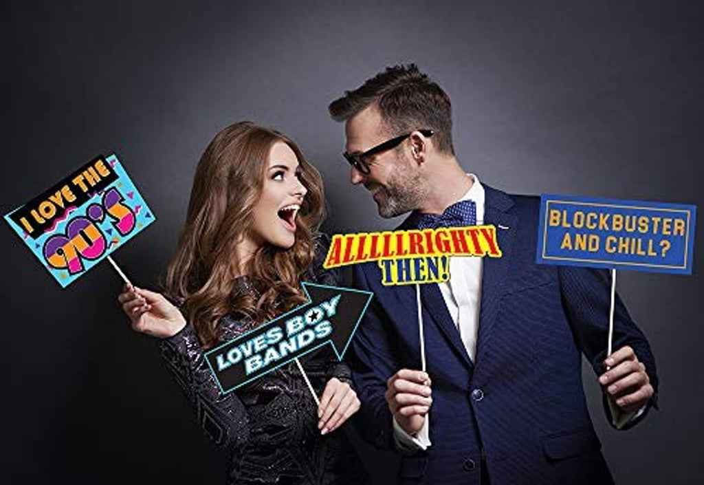 90s photo booth prop signs on sticks, including 'Love the 90s' and 'Blockbuster and Chill?'