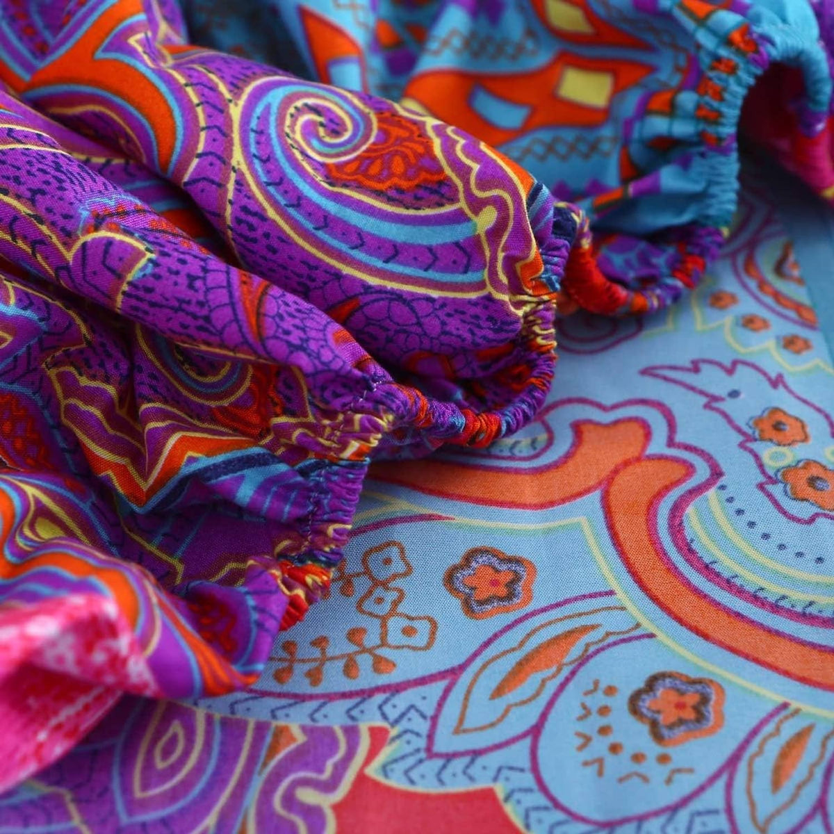 Close-up of folded boho paisley fabric in purple, teal, and orange patterns