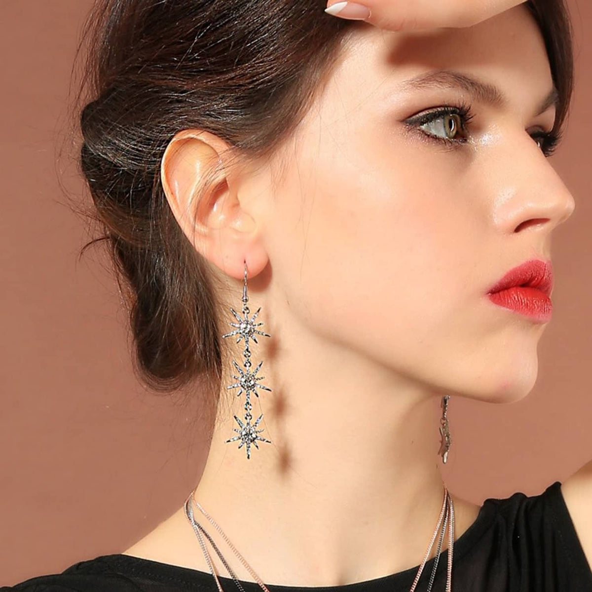 Snowflake dangle earrings on model, silver-toned with three dangling crystal snowflakes
