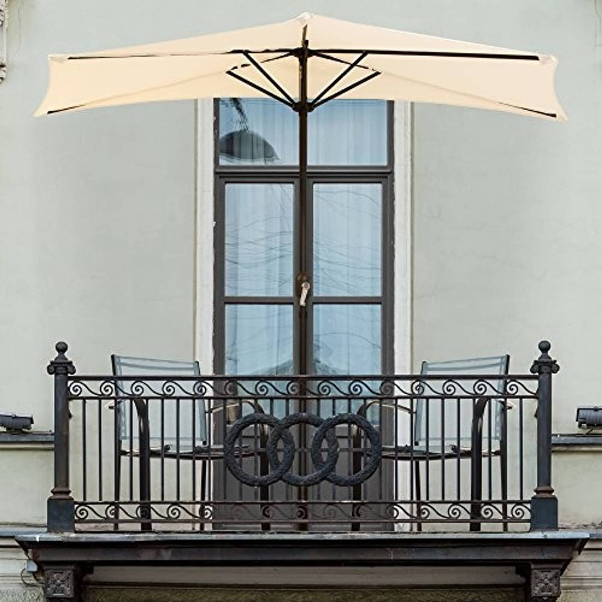 Tan half-round patio umbrella over balcony railing with window behind