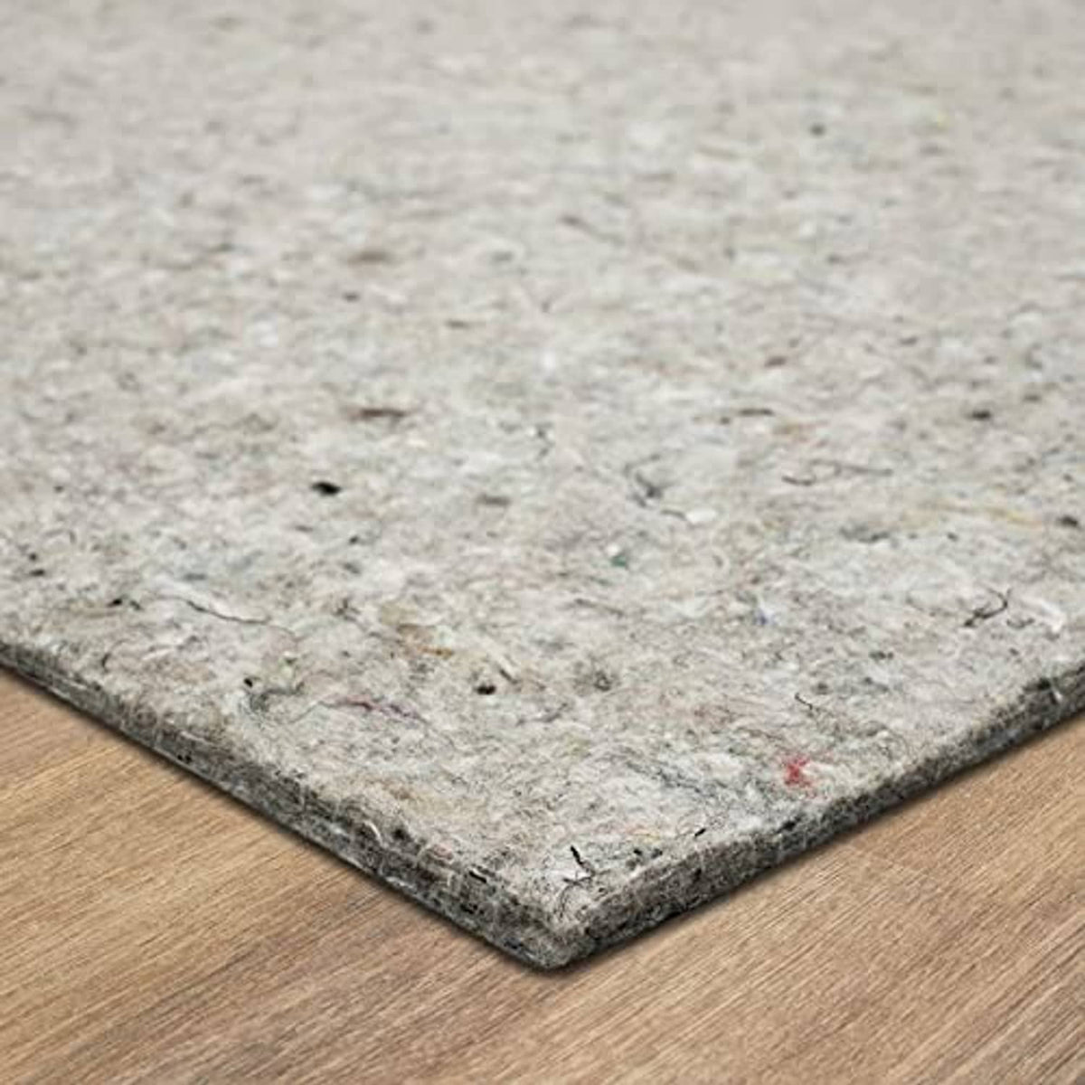 Light gray felt rug pad corner on wood floor, thick protective cushion