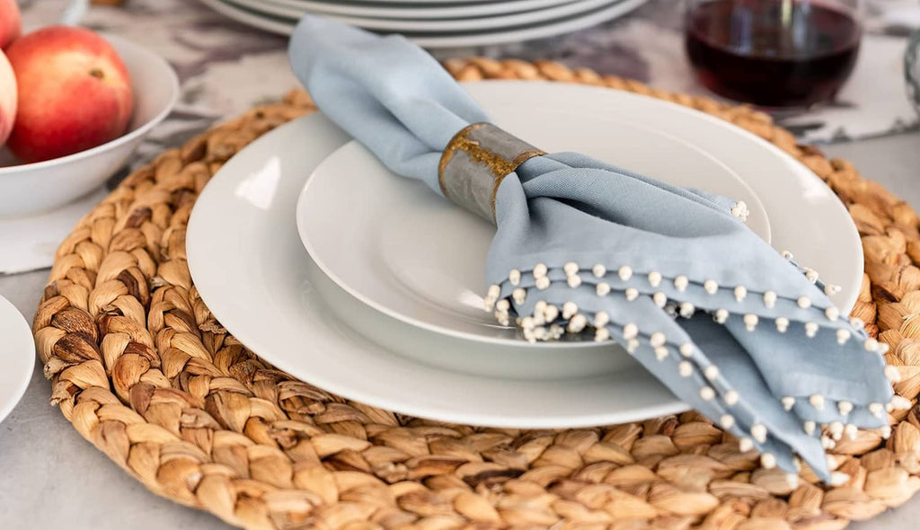 White round shallow plate with light-blue napkin on woven placemat