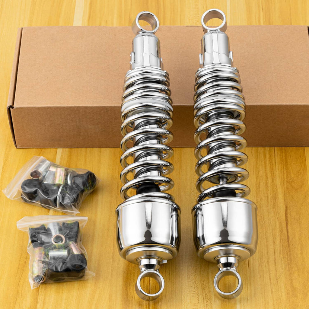 Two chrome rear shocks on cardboard with coiled springs and accessory hardware pieces