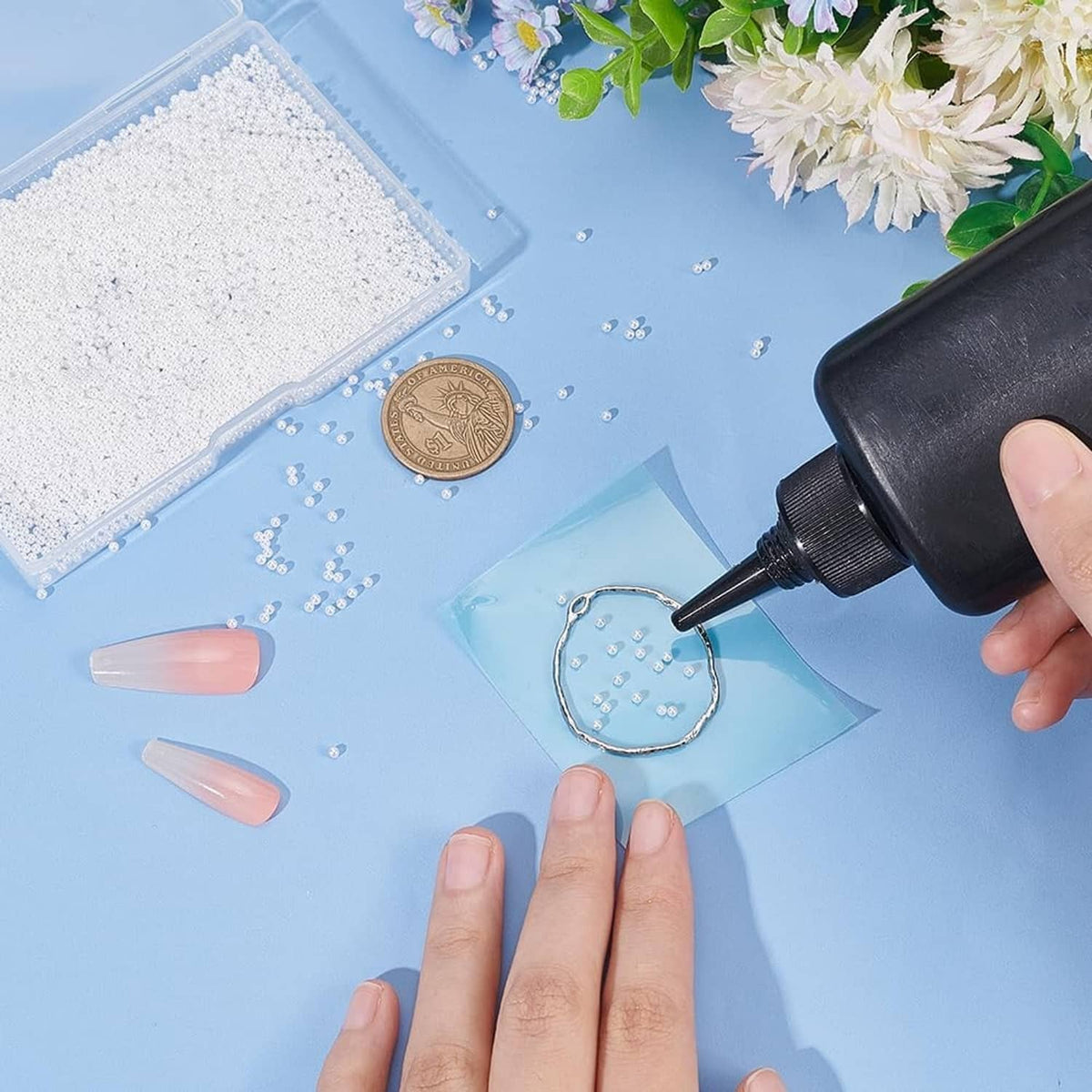 White pearl beads scattered across a craft work surface with hands and tools