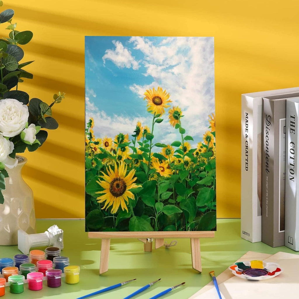 Painted sunflower art on a small easel with wooden craft boards and paint jars